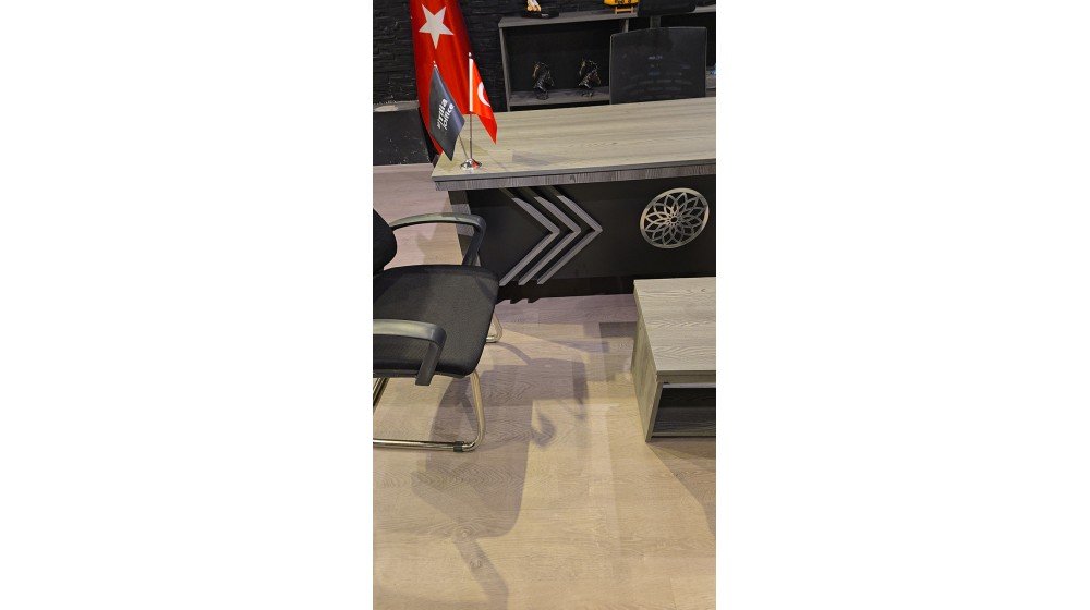 Gri modern Meridyen yönetici masası, ön panelinde CNC kesim geometrik ve dairesel motif, ofis ortamında Polen misafir koltukları ile sergileniyor.